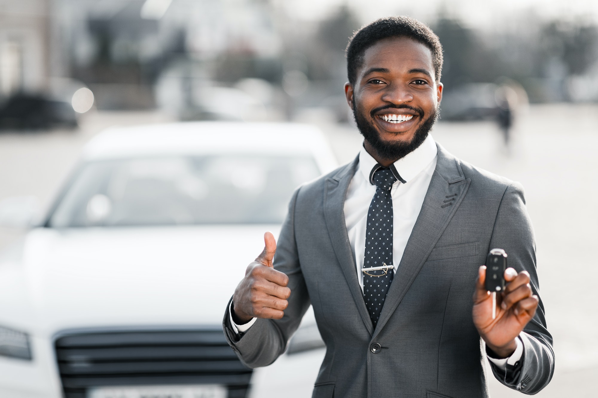 Car Rental. Happy Man Holding Key And Showing Thumb Up